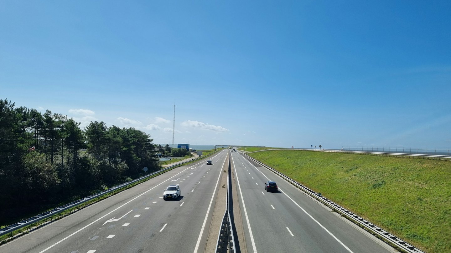 Autos fahren auf einer mehrspurigen Autobahn in der Nähe von grünen Wald Bäumen.